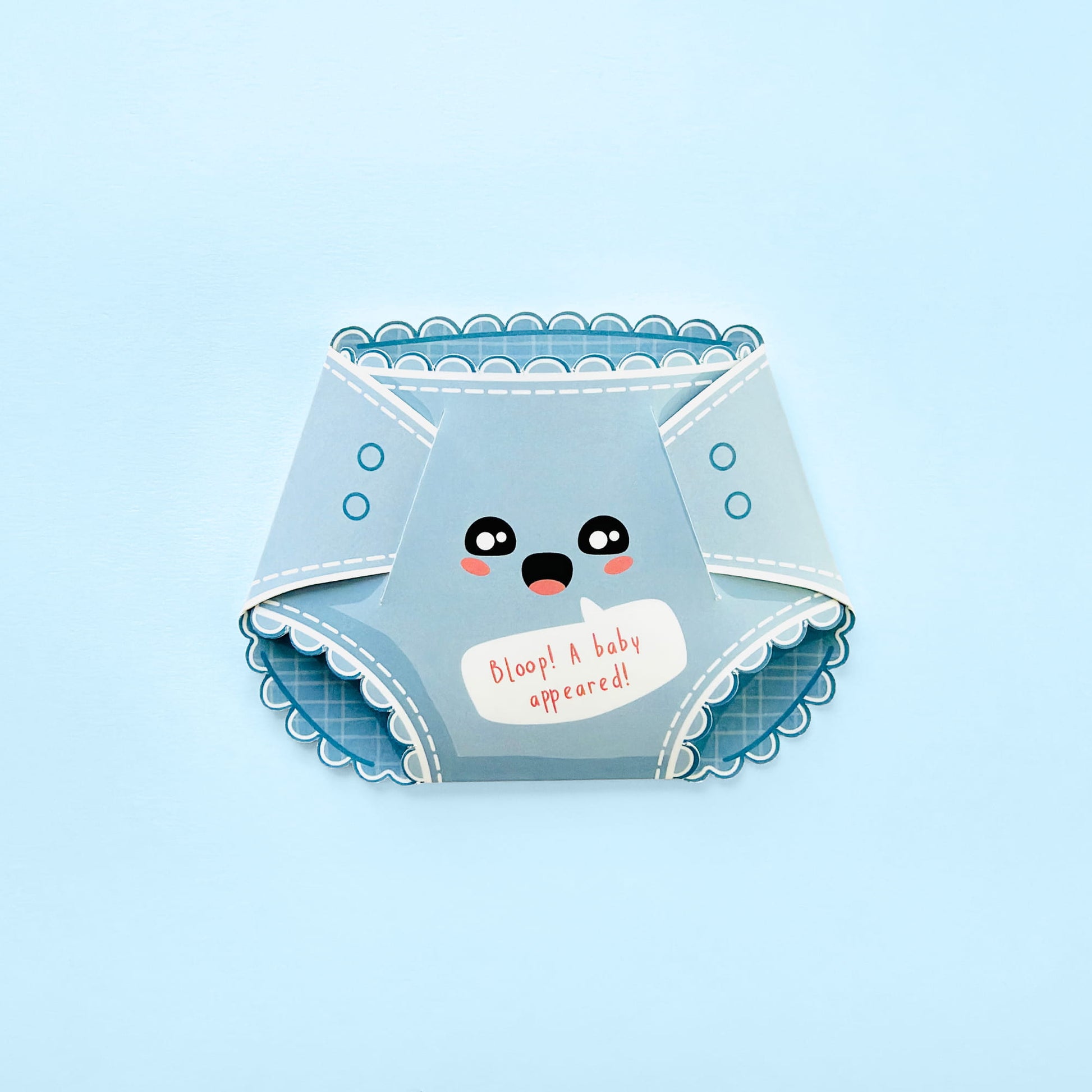 A light blue novelty diaper-shaped card with a cute cartoon face and the text 'Bloop! A baby appeared!' on a light blue background.