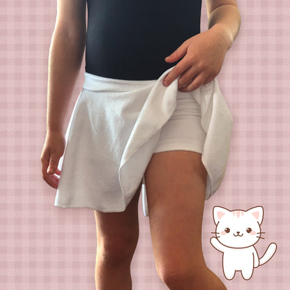 Person wearing a black top and white shorts on a pink checkered background with a cartoon cat icon.