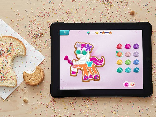 Tablet displaying a cookie design feature in My Little Pony Mane Merge, surrounded by cookies and sprinkles.